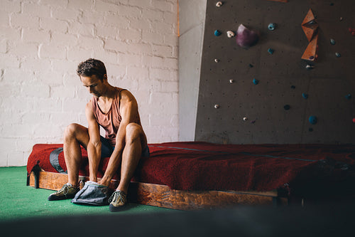 Man wall climber coating hands with gripping powder