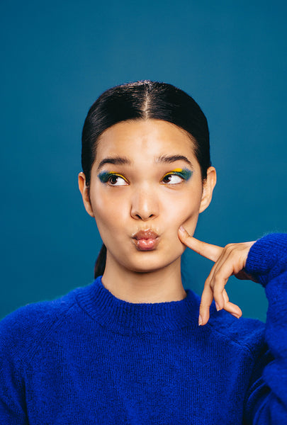 Woman with bold straight line eyeliner pouts and makes a face in a studio