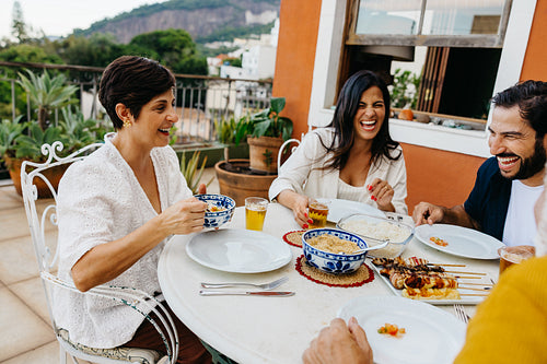 Friends enjoying a meal with barbecue skewers on a sunny patio