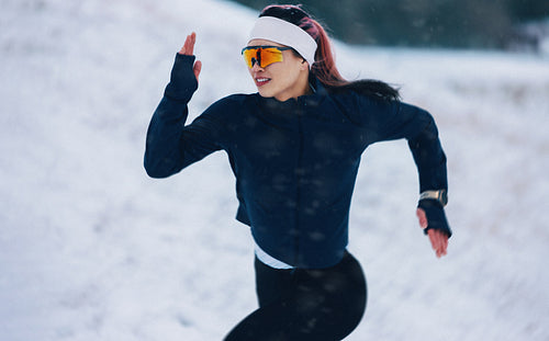 Trail running shows the woman working through winter snow during fitness training