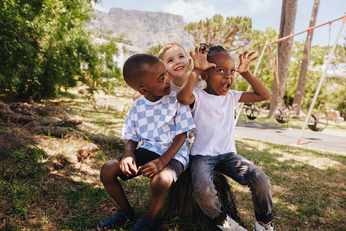 Three children enjoying playtime together outdoors in a sunny park