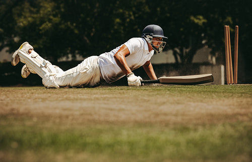 Cricketer diving to reach safety during an intense game on a sunny day