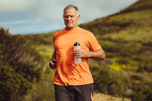 Senior man in fitness clothes running outdoors