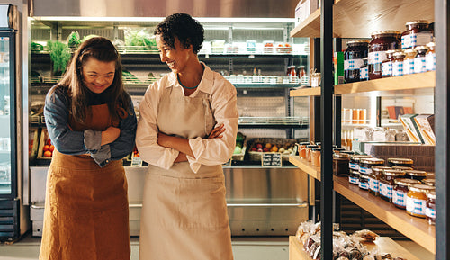 Two grocery store workers laughing happily in their shop