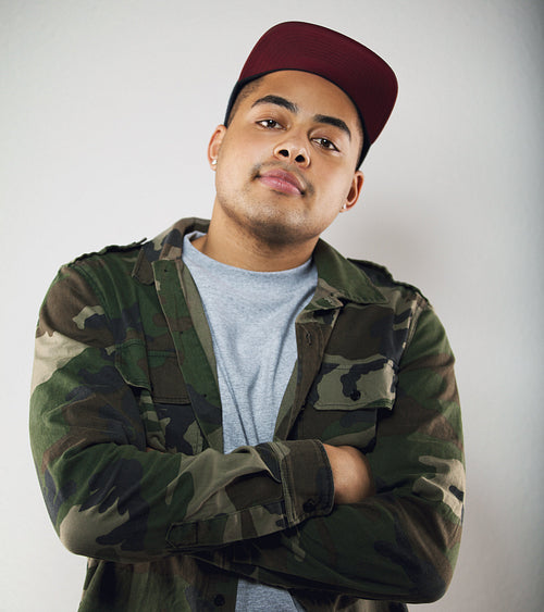 Casual young man wearing camouflage jacket posing on grey background