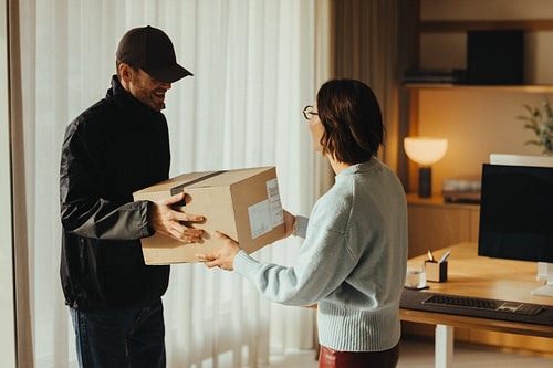 Delivery driver hands a package to a customer at work