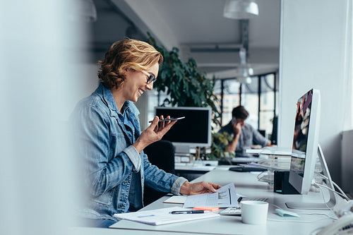 Businesswoman talking on smartphone and looking at documents