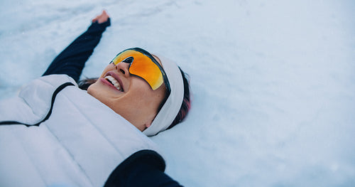 Woman making a snow angel in winter outdoor fun scene