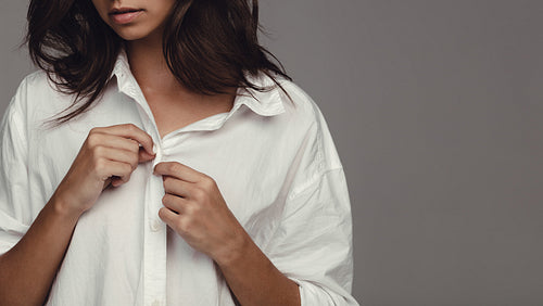 Woman undressing against grey background