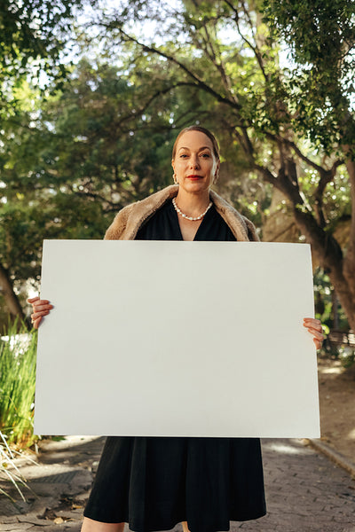 Confident posh woman holding up a banner outdoors
