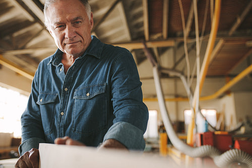 Senior carpenter inspecting the wooden bar