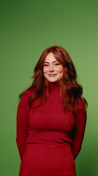 Happy woman in red smiles, winks and laughs against a green screen