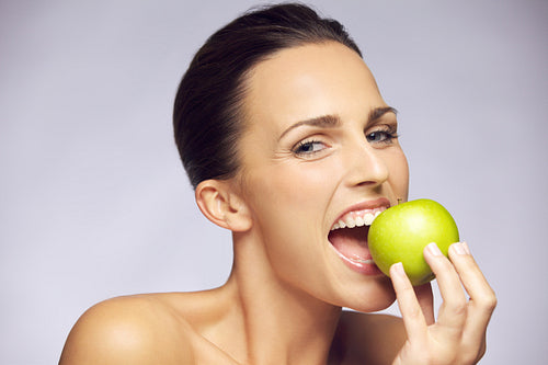 Young happy woman eating green apple