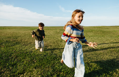 Playful children run across wide field