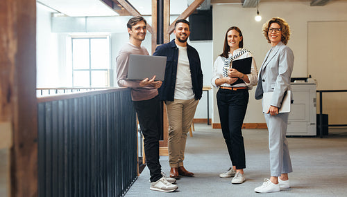 Group of tech professionals looking at the camera as they stand together in an office