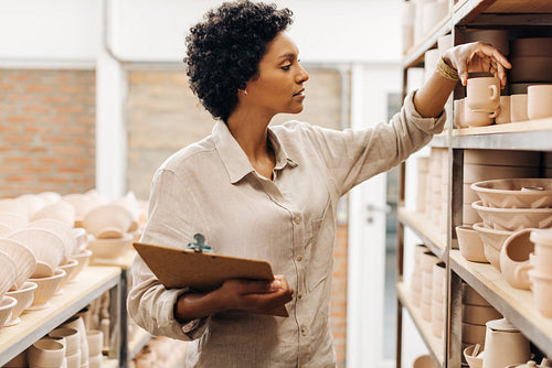 Female ceramic shop owner examining one of her earthenware products