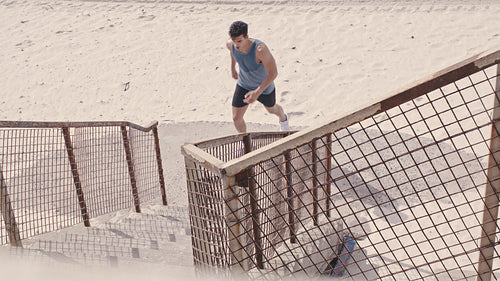 Fit man running up the steps on beach