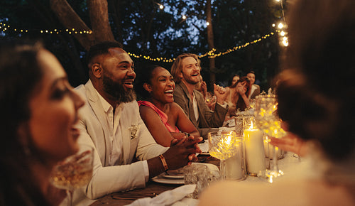 Friends enjoying an intimate candlelit wedding with laughter and joy in a garden