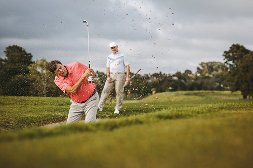 Golfer hitting the ball out of a sand bunker
