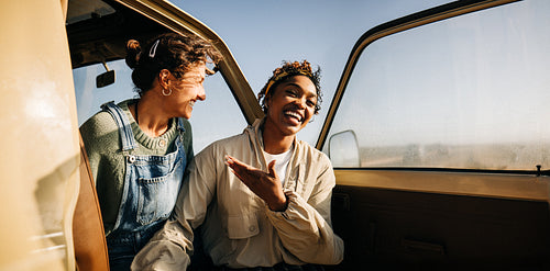 Friends in a vintage car share laughter on a sunny day