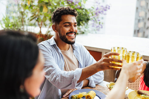 Latino friends sharing a toast during a cheerful outdoor meal gathering