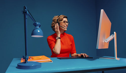 Agent with headset typing on keyboard in colour blocking office setting