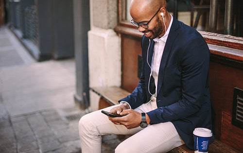 Happy businessman listening music with phone outdoors