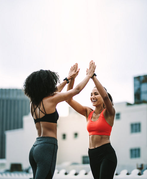 Women athletes giving high five during workout on rooftop