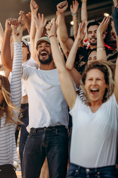 Excited sports fans cheering at live game in stadium