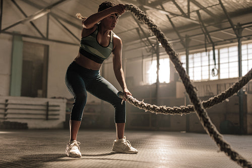 Athlete working out with battle ropes at cross gym
