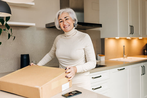 Elderly woman unpacking a delivery box at home