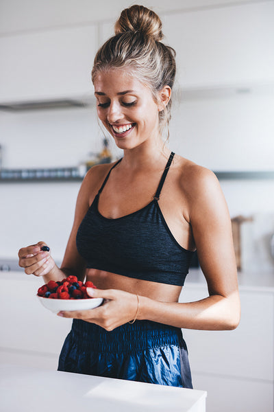 Happy female in kitchen eating fresh berries