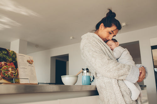 Loving mother carrying her newborn boy in kitchen
