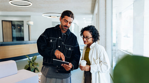 Man and woman review tablet in office lobby