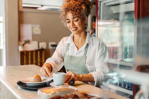 Mature female barista serving an order in a cafe