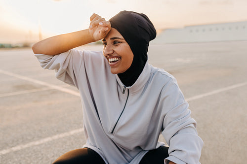 Happy Muslim sportswoman wiping off her sweat outdoors