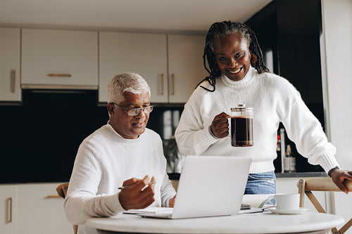 Happy mature woman bringing her working husband some coffee