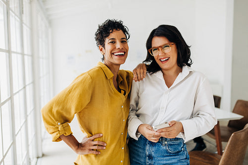 Happy female colleagues standing together in an office