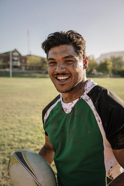 Smiling rugby player smeared in mud