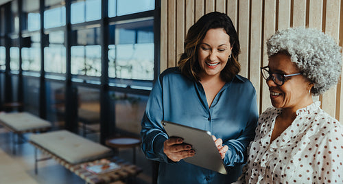 Two female business partners discussing strategy with tablet in office
