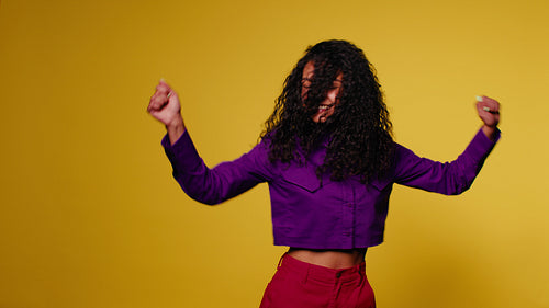 Happy woman dancing and laughing on a yellow background