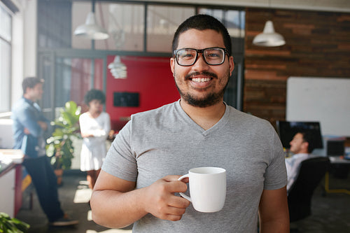 Smiling creative professional having coffee in office