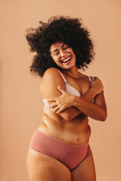 Happy curvy woman embracing her body in a studio
