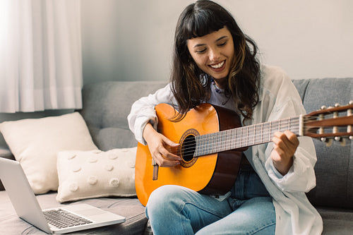 Happy female guitarist giving an online lesson
