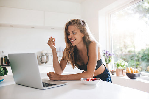 Beautiful young woman in kitchen with laptop