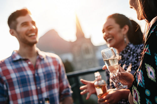 Friends standing together on rooftop with drinks