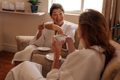 Female friends having herbal tea and chatting in spa