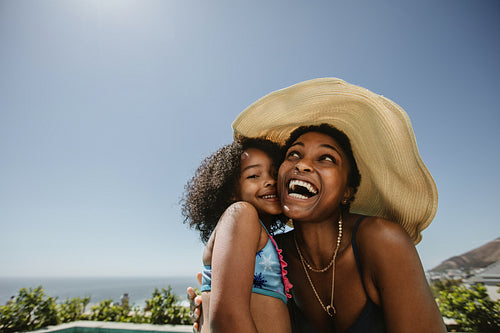 Woman with her daughter having fun at the poolside