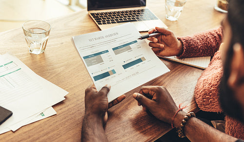 Coworkers sitting at work desk with business papers and laptop