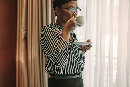 Businesswoman on business trip drinking coffee in hotel room